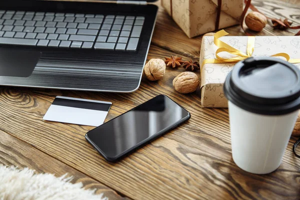 Online Kredi kartı ile Noel tatili için alışveriş. Dizüstü bilgisayar, akıllı telefon ve hediyeler ahşap tablo.