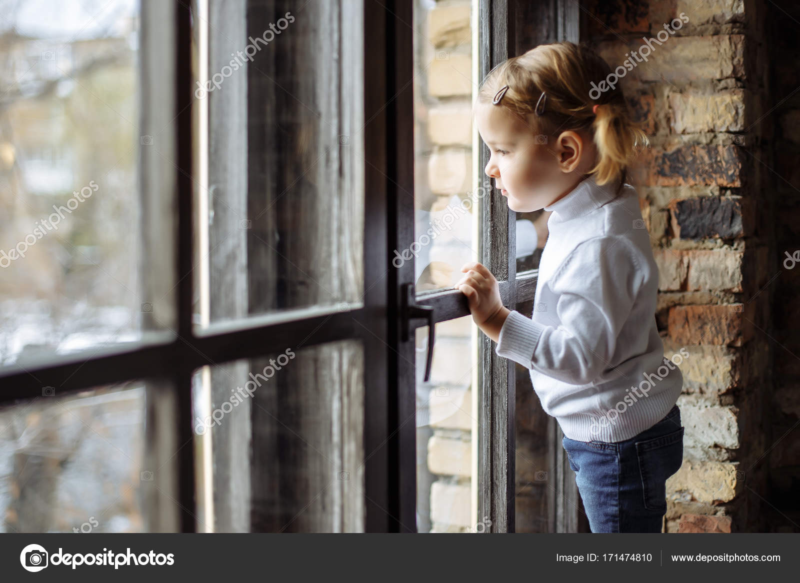 Trauriges Kind schaut aus dem Fenster. Stockfotografie