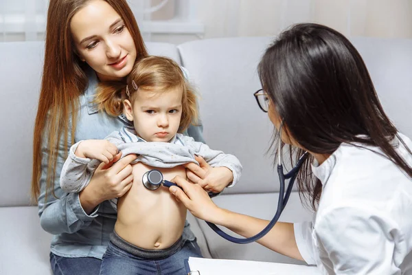 Pédiatre femme examinant une petite fille avec stéthoscope. Mère tenant son enfant. Médecin rendre visite à son patient à la maison — Photo