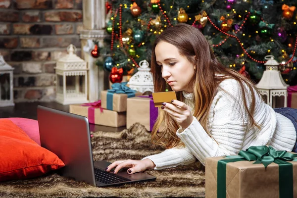 Молодая женщина делает онлайн покупки с кредитной картой и ноутбуком дома. Рождественские покупки — стоковое фото