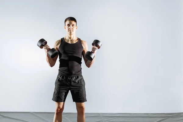 Joven hombre fuerte haciendo ejercicio con pesas en el gimnasio —  Fotos de Stock