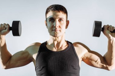 Güçlü delikanlı egzersiz gri arka plan üzerinde dumbbells ile