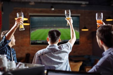 Mutlu futbol taraftarları. Üç arkadaş barda bir oyun izlerken.