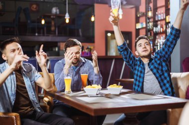 Neşeli arkadaşları Tv ve içme bir futbol maçı izlemek eğlenceli sahip sayacı pub, bar, bira taslak.