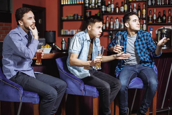 Молодые люди с пивом смотрят матч в баре — стоковое фото