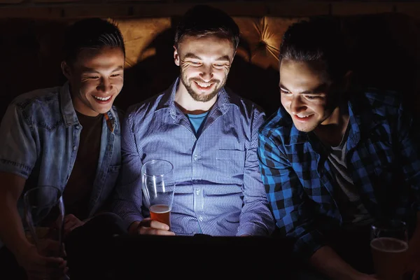 Três jovens alegres assistindo um filme no escuro . — Fotografia de Stock