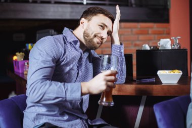 Bira içip bardaki televizyonda maç izlerken yakışıklı delikanlı.