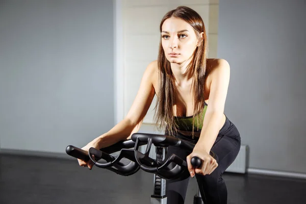 spor salonunda egzersiz bisikleti üzerinde çalışan kadın uygun