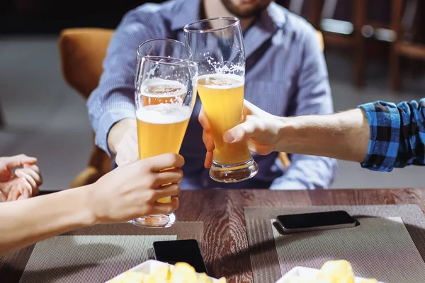 Tres amigos brindando con vasos de cerveza ligera en el pub — Foto de Stock