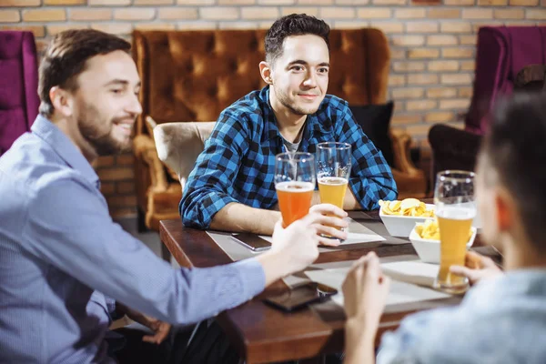 Люди, мужчины, отдых, дружба и концепция празднования - счастливые друзья-мужчины разговаривают и пьют пиво в баре или пабе — стоковое фото
