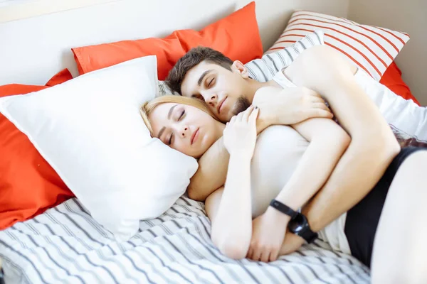 Boldog fiatal pár alszik az ágyban reggel és átölelve, a szeretet és a kapcsolatok fogalma — Stock Fotó