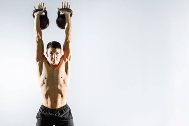 Güçlü delikanlı egzersiz gri arka plan üzerinde dumbbells ile.