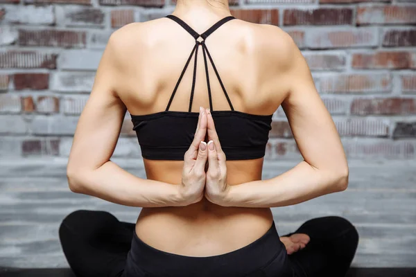 Close-up mãos de jovem praticando ioga com namaste atrás das costas, sentado em exercício de seiza, pose de vajrasana, casa interior fundo — Fotografia de Stock