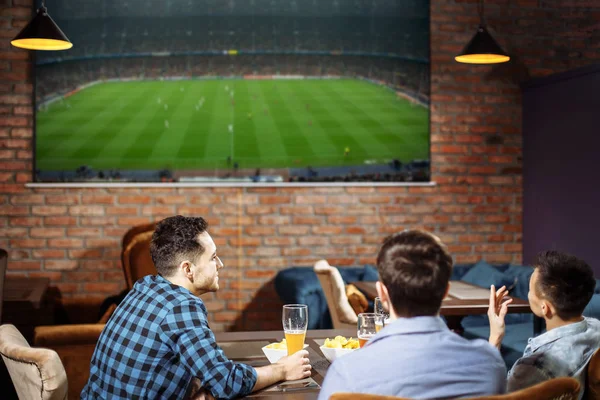 Amis heureux ayant des loisirs dans le pub regarder le sport à la télévision ensemble boire de la bière — Photo