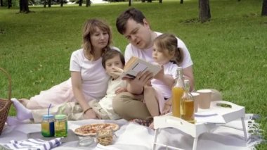 Piknik sırasında çimlerin üzerinde dinlenen çocukları olan mutlu bir aile. Aile hayatında mutluluk ve uyum.