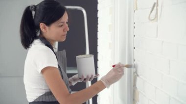 Kadın işçi evin duvarlarını fırçayla boyuyor. İnşaat, onarım ve yenileme