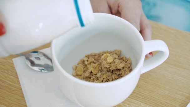 健康的な朝食 牛乳やヨーグルトをシリアルのボウルに注ぐ女性の手 — ストック動画