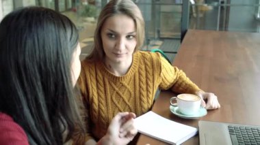 Bir kafede ya da ofiste konuşan ve kahve içen genç kadınlar.