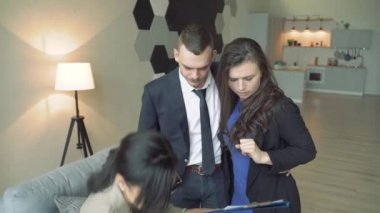 Profesyonel emlakçı genç bir çifte dairenin ya da evin anahtarlarını veriyor..