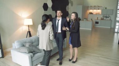 Profesyonel emlakçı genç bir çifte dairenin ya da evin anahtarlarını veriyor..