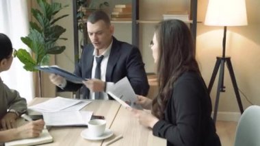 Genç erkek şirket lideri ofisteki bir toplantıda ekibe talimat veriyor.