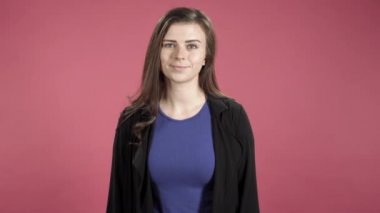Gülümseyen ve pembe arka planda duran mutlu genç kadın..