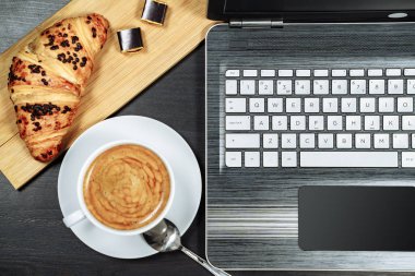 Kahve, kruvasan ve dizüstü bilgisayar masada. Kahvaltı..