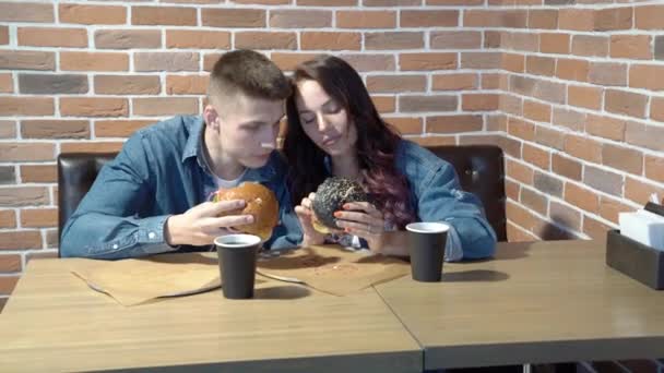 Αγαπώντας Ζευγάρι Χαριτωμένο Μιλάμε Και Τρώγοντας Χάμπουργκερ Ένα Καφέ — Αρχείο Βίντεο
