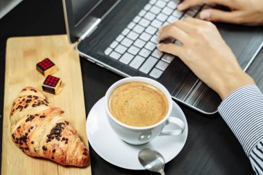 Masaüstünde çikolata ve kahve olan kruvasan. İş kahvaltısı kavramı.