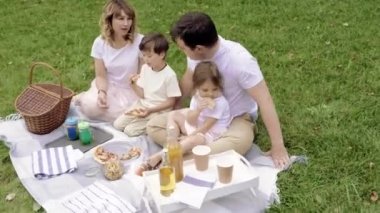 Mutlu aile pizza yiyor ve piknikte eğleniyor.