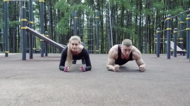 アスリートの女性と男性が板の屋外に立っている フィットネスの人々が一緒にトレーニング — ストック動画
