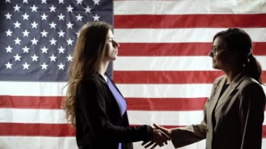 Amerikan bayrağının arka planında iki iş kadınının siluetleri. Görüş düellosu