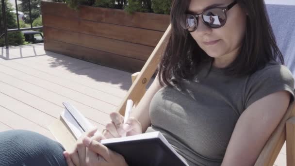 Jeune Femme Lunettes Soleil Prenant Des Notes Dans Carnet Extérieur — Video