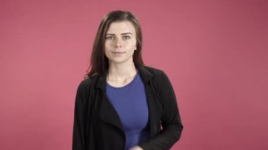 Kollarını göğsünde pembe arka planda birleştiren ciddi bir kadının portresi..