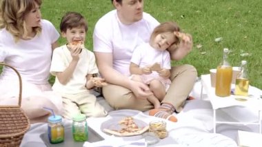 Mutlu aile pizza yiyor ve piknikte eğleniyor.