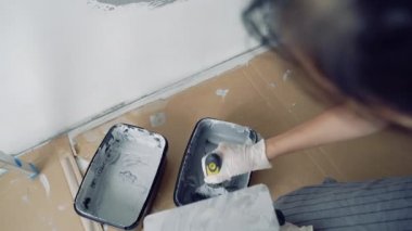 Gri boya ya da alçıyı spatulayla karıştıran eldivenli kadın ellerini kapat.