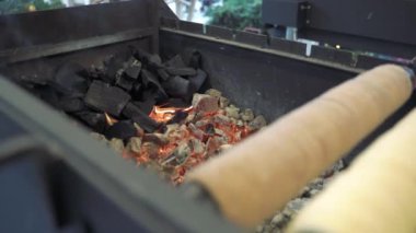 Elleri dışarıda yemek pişirmek için kömür karıştırıyor.
