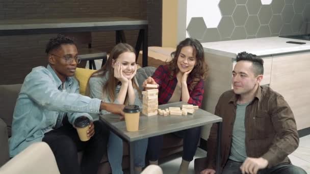 Groupe d'amis multinationaux jouant jeu de retrait de bloc dans le salon à la maison 