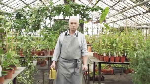 Ein Älterer Mann Schürze Mit Werkzeug Und Gießkanne Geht Durch — Stockvideo