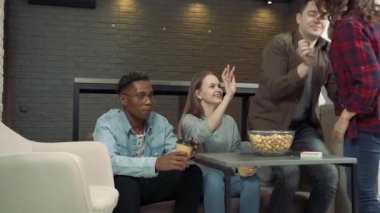 Bir grup arkadaş yeni kız arkadaşlarını karşılıyor. Evdeki oturma odasında konuşup gülüyorlar.