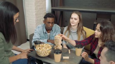 Bir grup mutlu arkadaş oturma odasında blok kaldırma oyunu oynuyor..