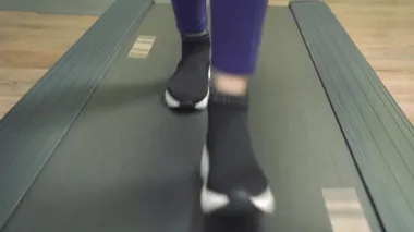 Spor ayakkabılı kadın bacaklarını kapat. Spor salonunda koşu bandında yürü.