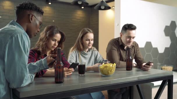 Багатоетнічна Група Друзів Активно Використовує Телефони Чотири Людини Ють Пиво — стокове відео