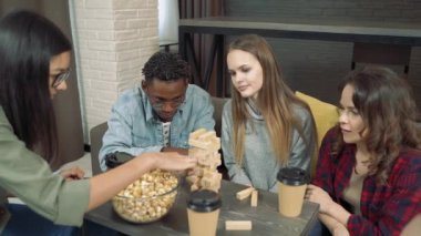 Evde blok kaldırma oyunu oynayan bir grup mutlu arkadaş.