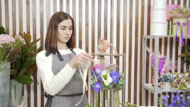 Joven florista decorando un arreglo de regalo de flores y vegetación en un taller o tienda — Vídeo de stock