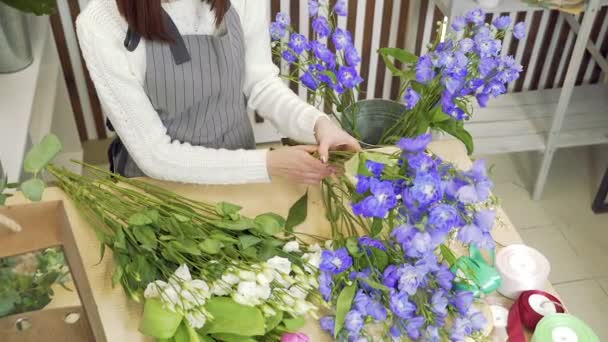 Ανθοπωλείο νεαρής γυναίκας που ελέγχει και επιλέγει τα καλύτερα λουλούδια για ένα μπουκέτο σε ένα εργαστήριο ή ανθοπωλείο — Αρχείο Βίντεο