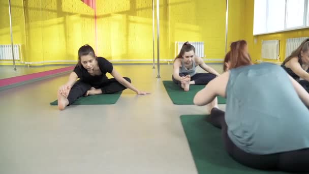 Skupina mladých zdravých žen na lekci strečink s instruktorkou ve třídě jógy — Stock video