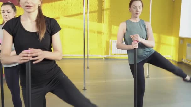 Spor salonunda antrenörle çalışan bir grup genç kadın pilates egzersizi yapıyor. — Stok video