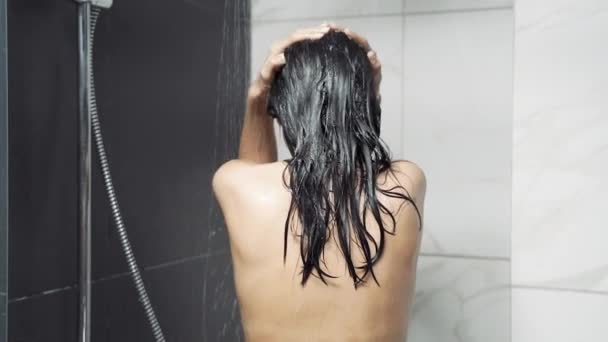 バスルームで若いブルネットの女性がシャワーを浴びて髪を洗う リラクゼーション ボディケアの概念 — ストック動画