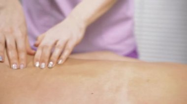 Güçlü kadın elleri, tıp merkezindeki genç bayana sırt, omuz ve boyun masajı yapıyor.